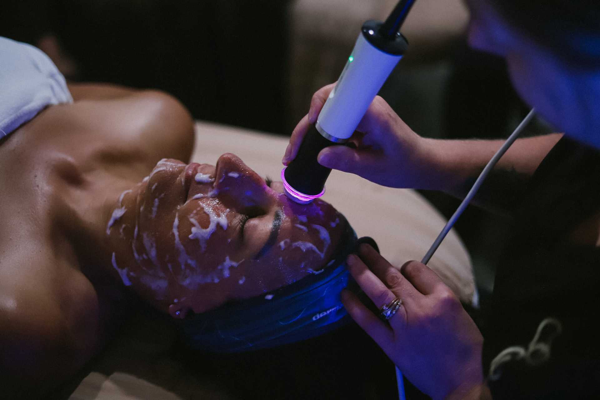 Person receiving a facial treatment with a device held by a specialist.