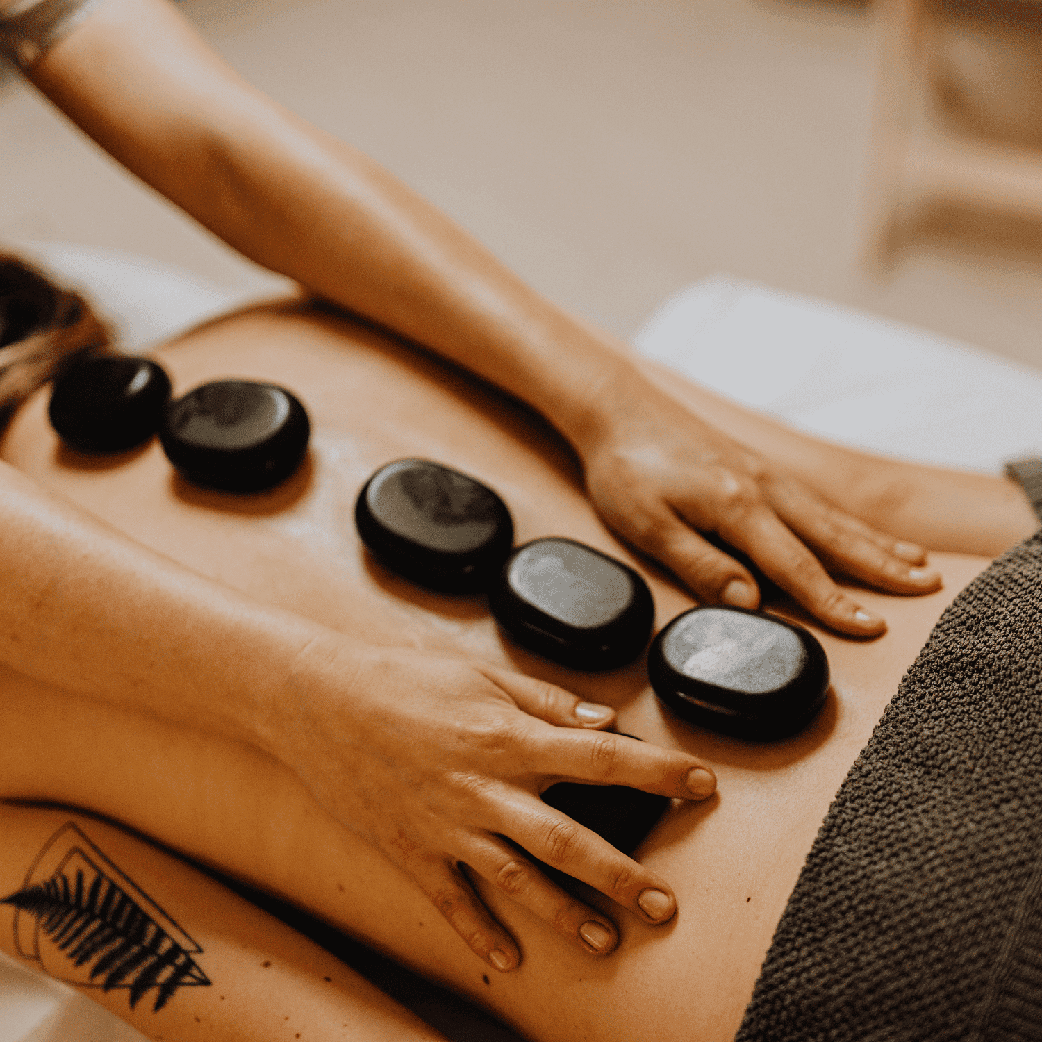 Hot stone therapy with smooth black stones on a person's back at a spa.