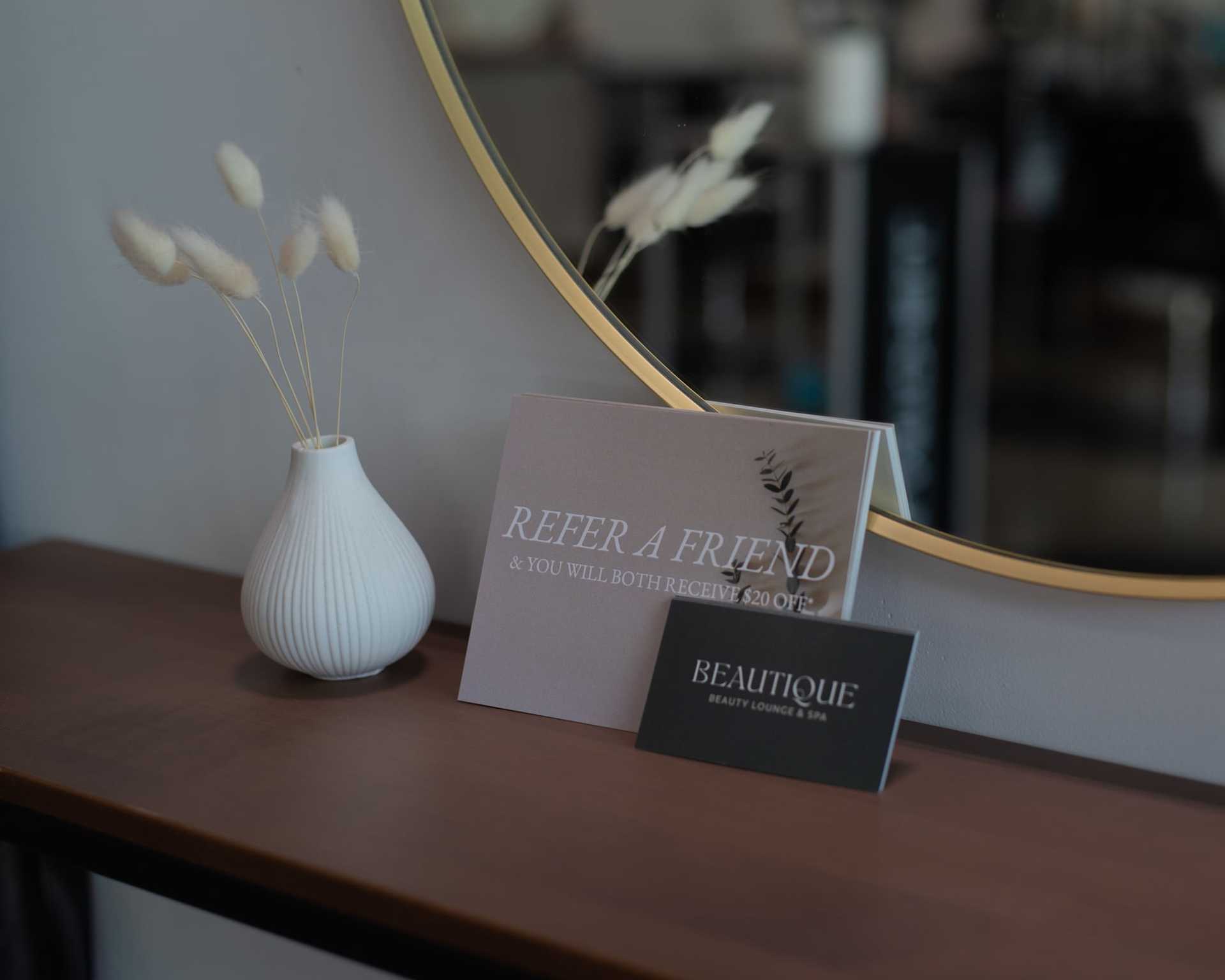 Refer a friend promotion displayed on a wooden table in a beauty lounge.