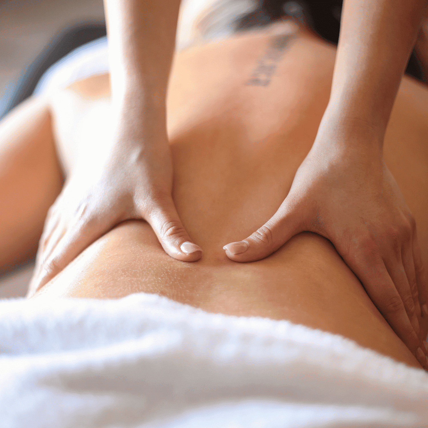Massage therapist performing a back massage on a relaxed client.